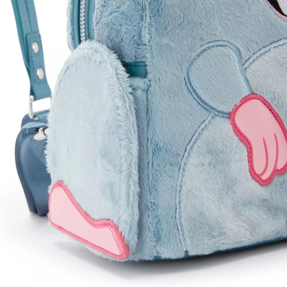 Close-up of a plush light blue bunny backpack with pink applique ears and a teal shoulder strap on a white background.