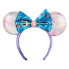 A mermaid-themed mouse ear headband featuring iridescent pink and white mermaid-scale ears, a large blue floral bow with a trident and pink gem accent, and a purple headband.
