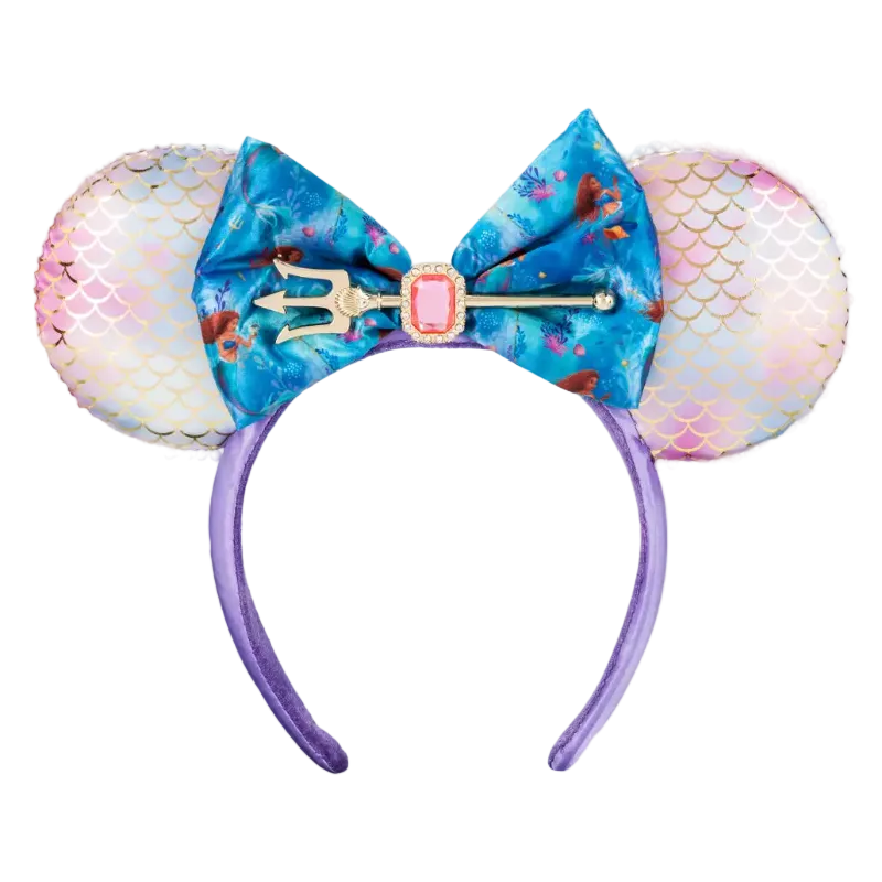A mermaid-themed mouse ear headband featuring iridescent pink and white mermaid-scale ears, a large blue floral bow with a trident and pink gem accent, and a purple headband.