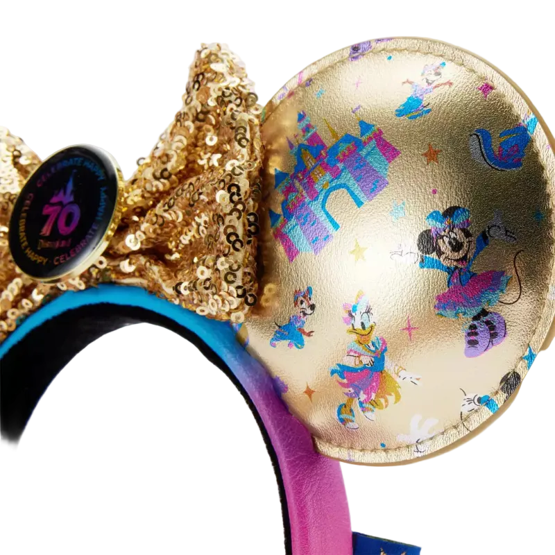 Close-up of a gold Minnie Mouse-themed headband with a sequined bow, a round gold ear printed with colorful Disney characters and motifs, and a black circular 10th Anniversary pin on a white background.