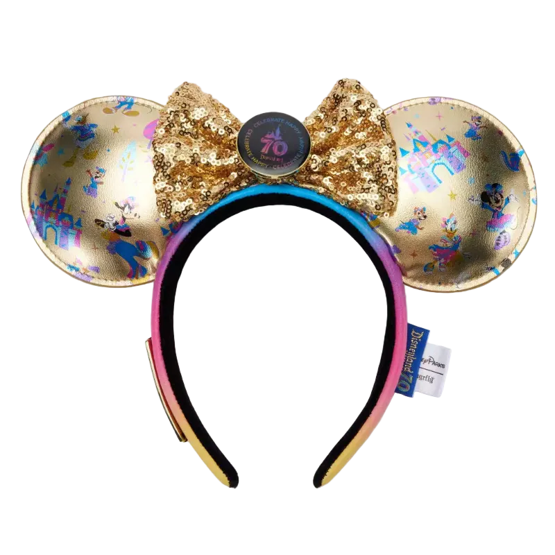 A Disney Minnie Mouse ears headband featuring gold sequined ears with holographic and blue monogram patterns, a large gold sequined bow with a central round button, and a black-to-pink gradient headband.