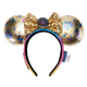 A Disney Minnie Mouse ears headband featuring gold sequined ears with holographic and blue monogram patterns, a large gold sequined bow with a central round button, and a black-to-pink gradient headband.