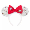 A pair of mouse ears headband featuring a large red bow in the center with cartoon character prints, and white ears with a black-and-white patterned fabric.