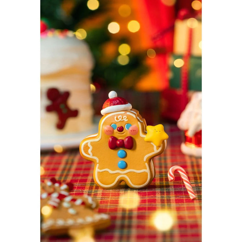 Decorative gingerbread man cookie with a star on a plaid tablecloth with Christmas decorations in the background.