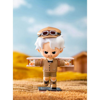 Toy figure of an aviator with goggles and a plane on a blurred outdoor background