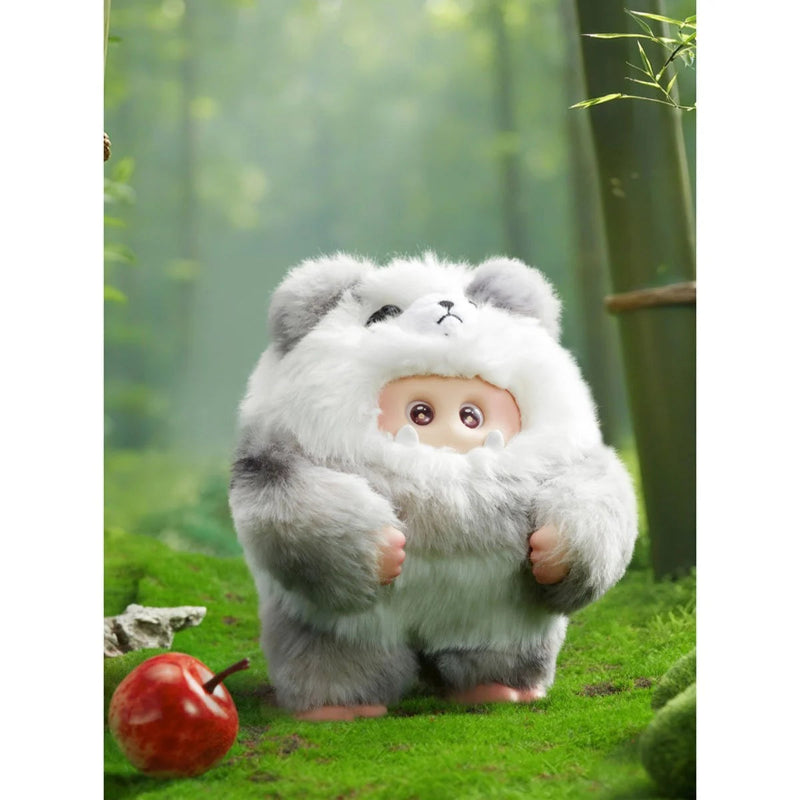 Plush toy resembling a creature with a fluffy white body and gray ears standing in a forest setting.