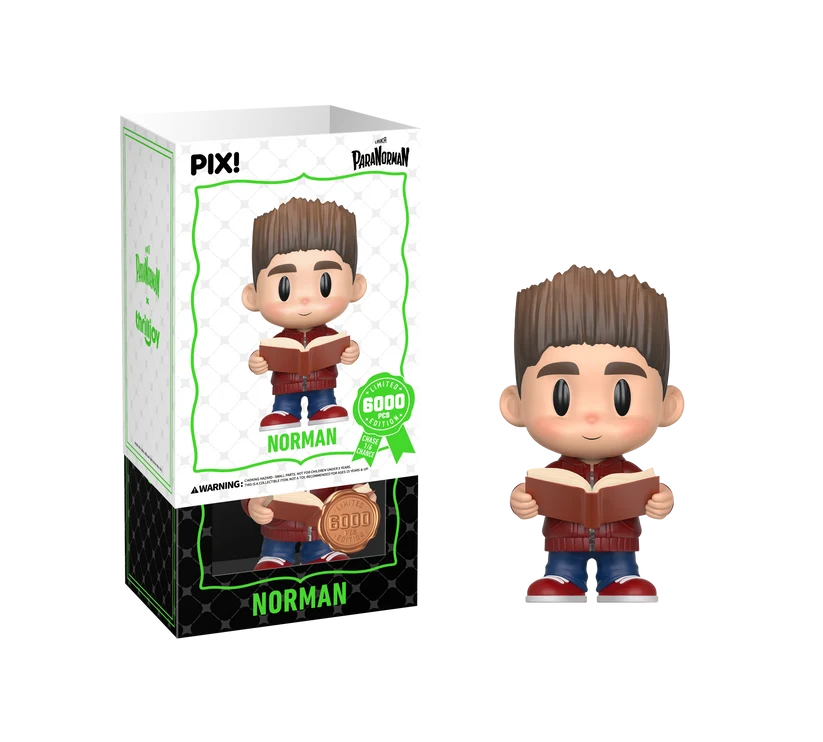 PIX! Norman vinyl figure in a red jacket and jeans holding an open book, shown beside its box with the white outer sleeve partly lifted.