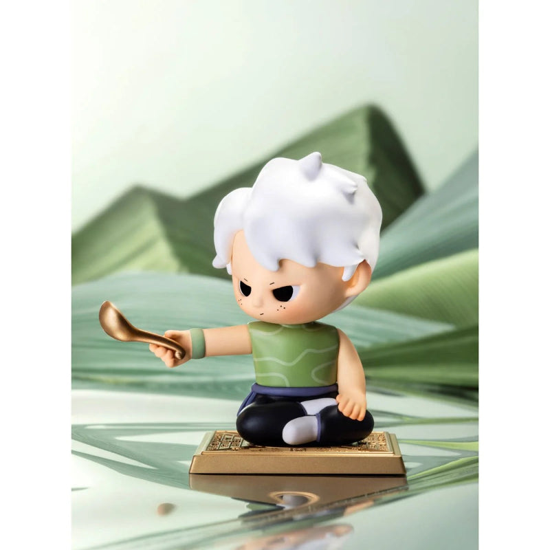 Animated character figurine with white hair and green shirt on a reflective surface with greenery in the background