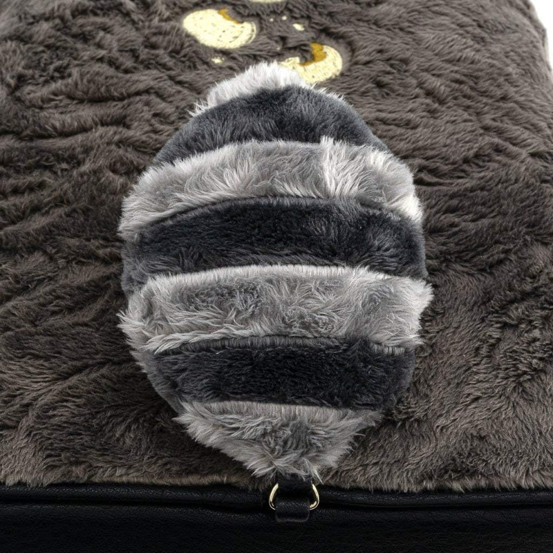 Close-up of a fluffy, gray and black bee-shaped pillow on a textured surface.