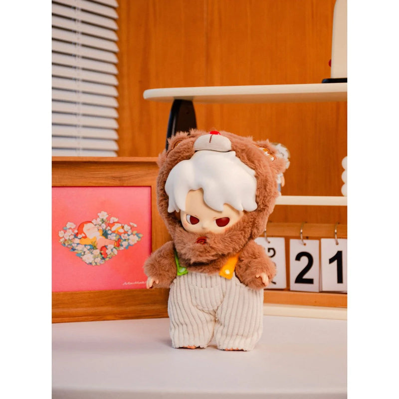 Plush toy resembling a character with a white hat and brown body on a wooden shelf.