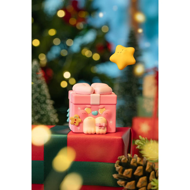 Pink toy gift box with a star on top, surrounded by Christmas decorations.