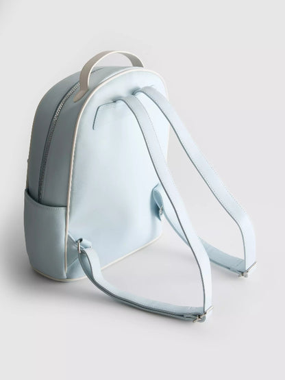 A light blue faux leather backpack shown from a three-quarters angle, featuring a top carry handle, adjustable shoulder straps, and a zippered main compartment on a light gray background.