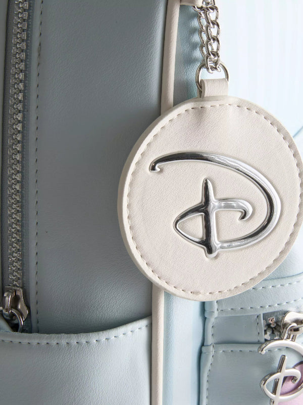 A close-up of a light blue leather bag featuring a round off-white leather Disney charm with a silver-tone Disney logo and chain.