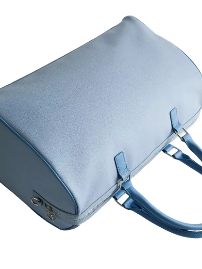 A light blue leather handbag with matching blue handles and silver-tone hardware, photographed on a clean light gray background.