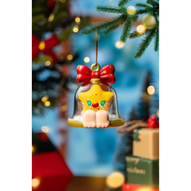 Decorative Christmas ornament with a star-shaped character under a bell, hanging from a tree.