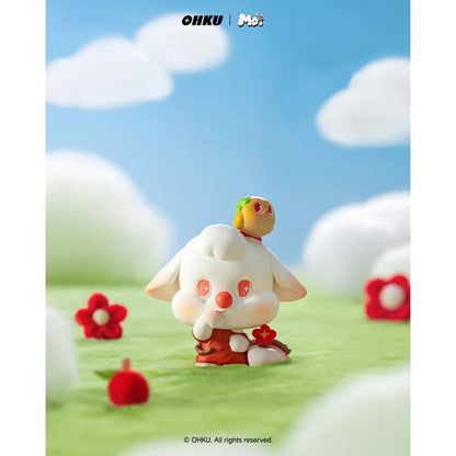 Small figurine with a red outfit and white face standing on grass with flowers and a blue sky.