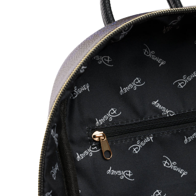 Close-up of a Disney backpack interior showing a black fabric lining with a repeating white Disney logo pattern, a black zipper pocket with a gold-tone pull, and part of the dark gray exterior with gold zipper trim.