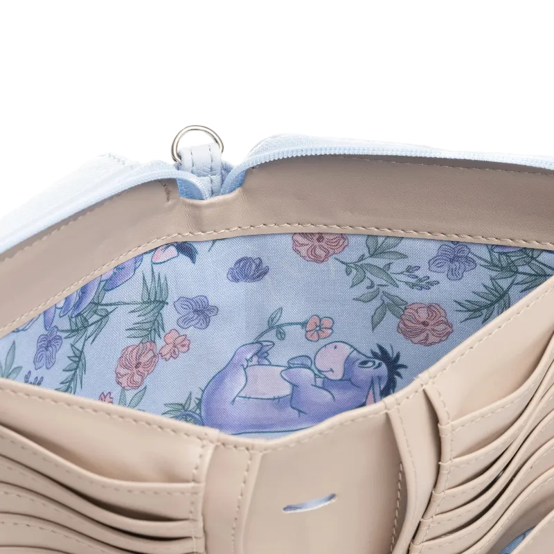 Close-up of a beige leather wallet or clutch showing a light blue floral interior with a purple cartoon donkey illustration and a silver zipper ring.