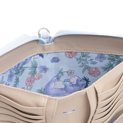 Close-up of a beige leather wallet or clutch showing a light blue floral interior with a purple cartoon donkey illustration and a silver zipper ring.