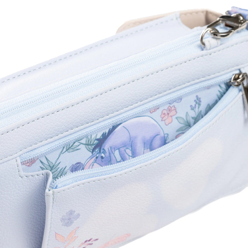 A close-up of a light blue faux-leather pouch featuring a floral and character print on the interior pocket, showing a purple Eeyore design with pink flowers and green leaves.