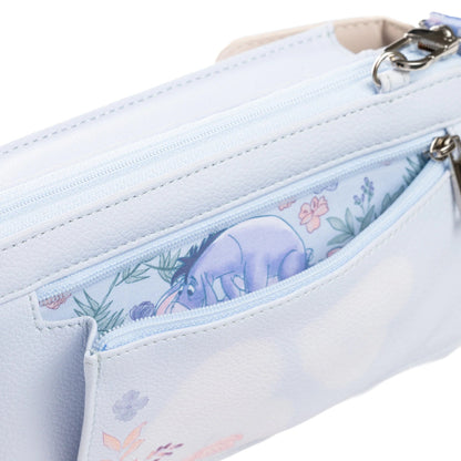 A close-up of a light blue faux-leather pouch featuring a floral and character print on the interior pocket, showing a purple Eeyore design with pink flowers and green leaves.