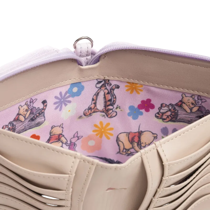 Close-up of a beige tote bag interior showing a light purple zipper and a pink fabric lining printed with Winnie the Pooh, Tigger, and other cartoon characters with colorful flowers.