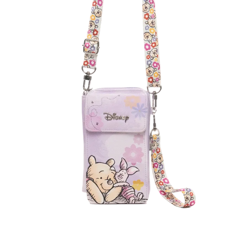 A Disney crossbody phone pouch in light purple, featuring Winnie the Pooh and Piglet illustrations, with a floral patterned strap and silver-tone hardware.