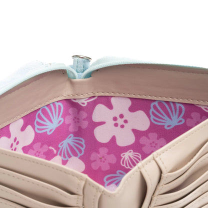 Close-up of a beige wallet or card holder showing a pink interior with a light blue and white floral and shell pattern.