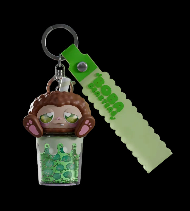 Keychain with a cartoon monkey design and green liquid, attached to a green tag with 'Bella' branding.