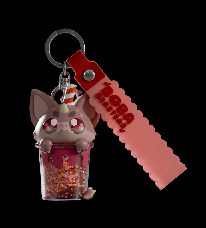 Keychain with a small figurine and red strap on a light gray background