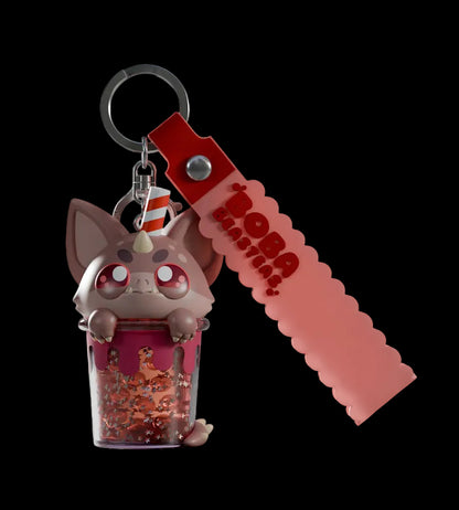 Keychain with a small figurine and red strap on a light gray background