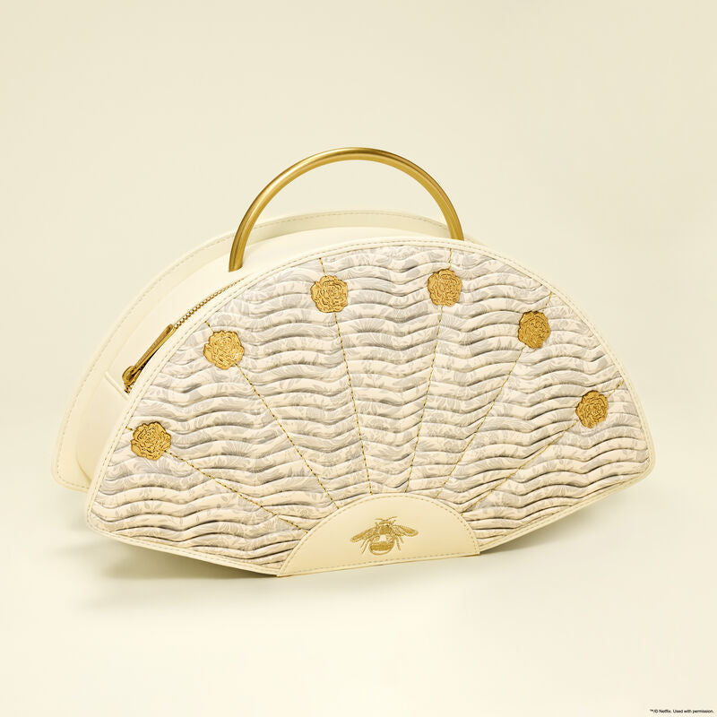 Cream-colored handbag with gold accents on a beige background