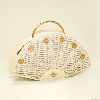 Cream-colored handbag with gold accents on a beige background