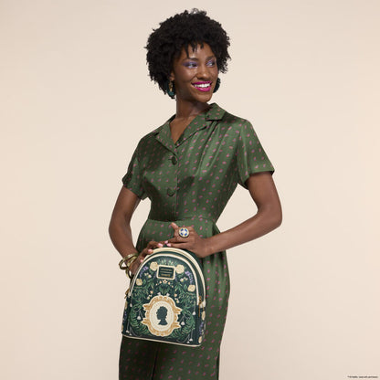 Woman in a green patterned dress holding a matching green backpack against a beige background