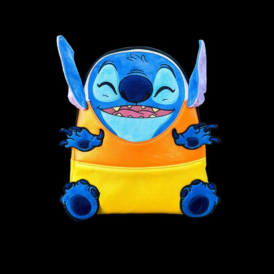 Candy corn-shaped plush toy with a character design on a wooden surface with pumpkins in the background