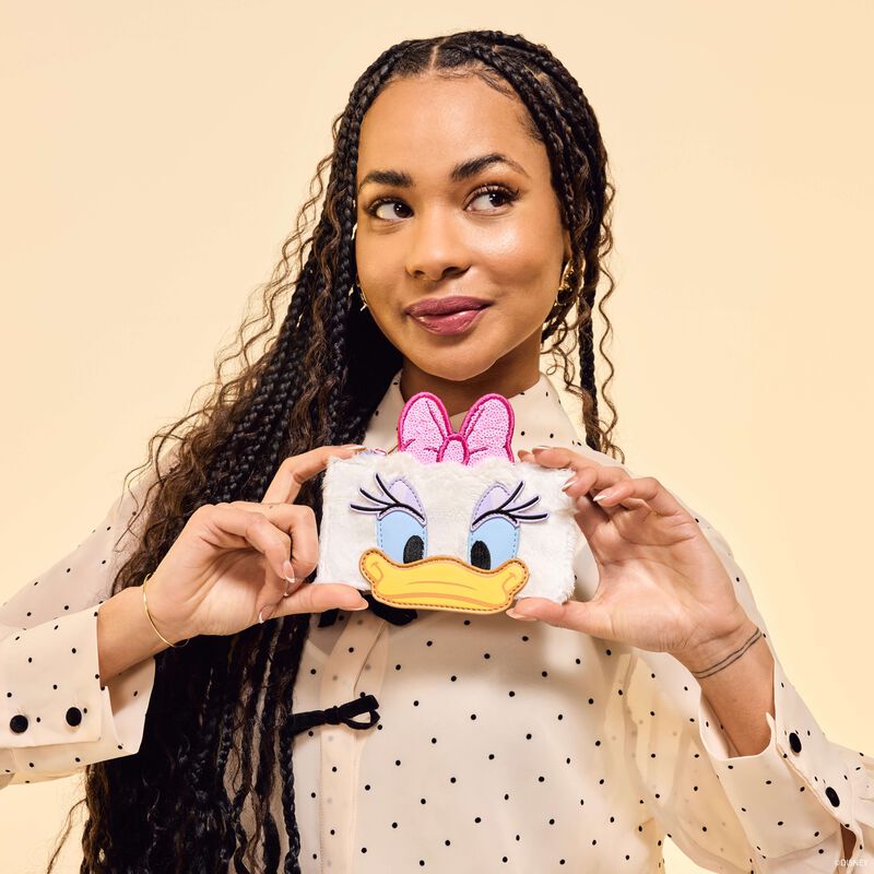 Woman holding a small pouch with a cartoon character design against a beige background