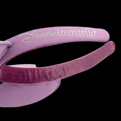 A close-up of a lavender purple Disney Loungefly headband featuring a lavender faux-leather top band with the brand name in white script and a darker purple velvet inner band, set against a plain white background.