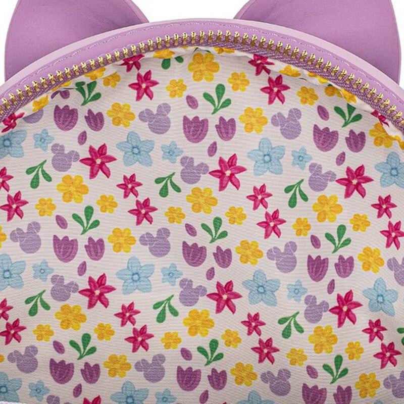 Close-up of a pastel floral patterned fabric with purple cat-ear shapes along the top edge and a gold zipper.