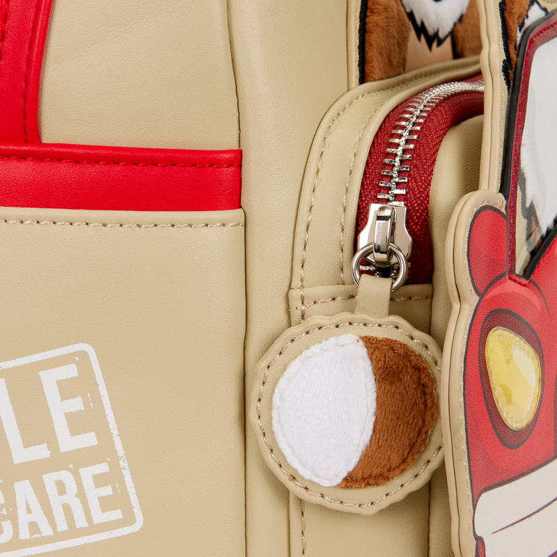 Close-up of a beige bag with a red zipper and a cartoon character keychain.