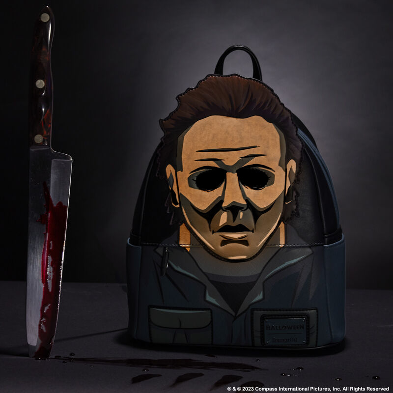 Backpack with a face design next to a knife on a dark background