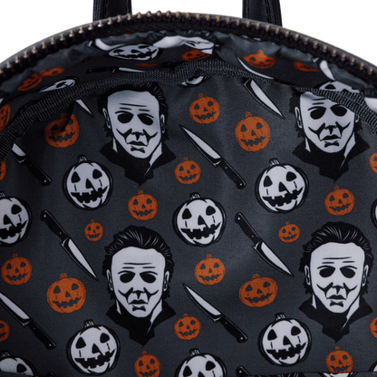 Backpack with Halloween-themed design featuring Michael Myers, pumpkins, and knives on a dark background.