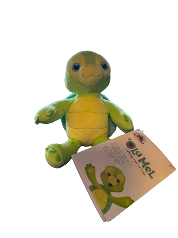 Green plush turtle toy with a matching packaging on a white background