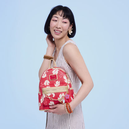 Woman holding a red floral backpack against a light blue background