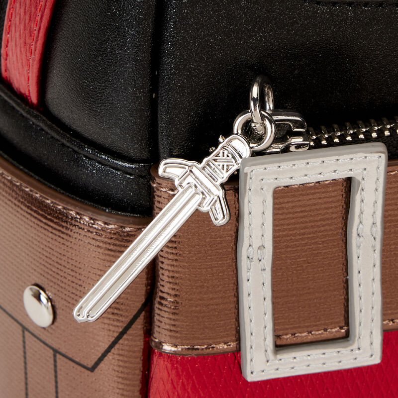 Close-up of a sword-shaped keychain attached to a multicolored bag.