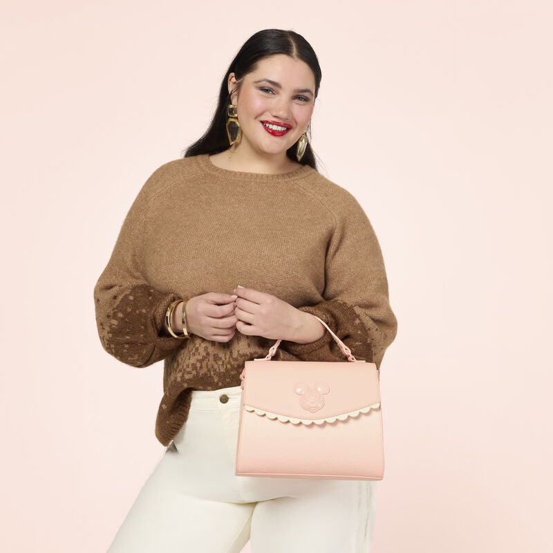 Woman holding a pink handbag against a light pink background