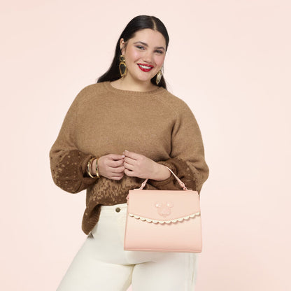 Woman holding a pink handbag against a light pink background