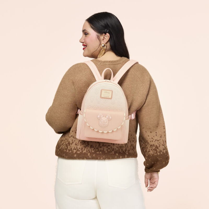 Woman wearing a brown sweater and pink backpack on a light pink background