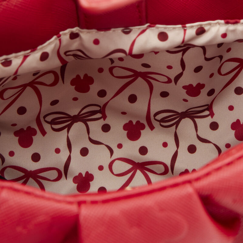 Close-up of a red fabric with a pattern of bows and polka dots.