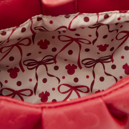 Close-up of a red fabric with a pattern of bows and polka dots.