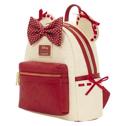Backpack with red and white polka dot bow, gold zippers, and Disney logo on a white background